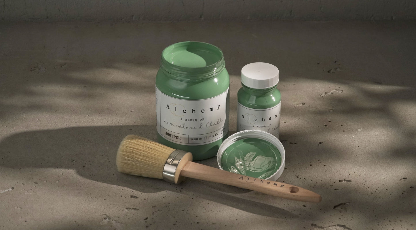 A jar of Alchemy by Fusion chalk paint in a mid-tone green color with blue undertones, labeled 'Juniper'.
