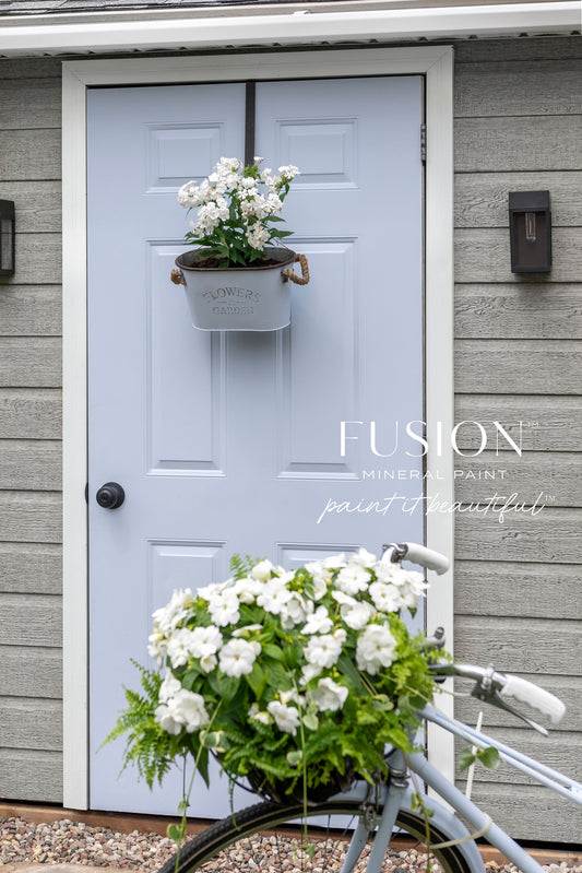 Light blue door with a hanging planter and white flowers, Fusion paint logo visible