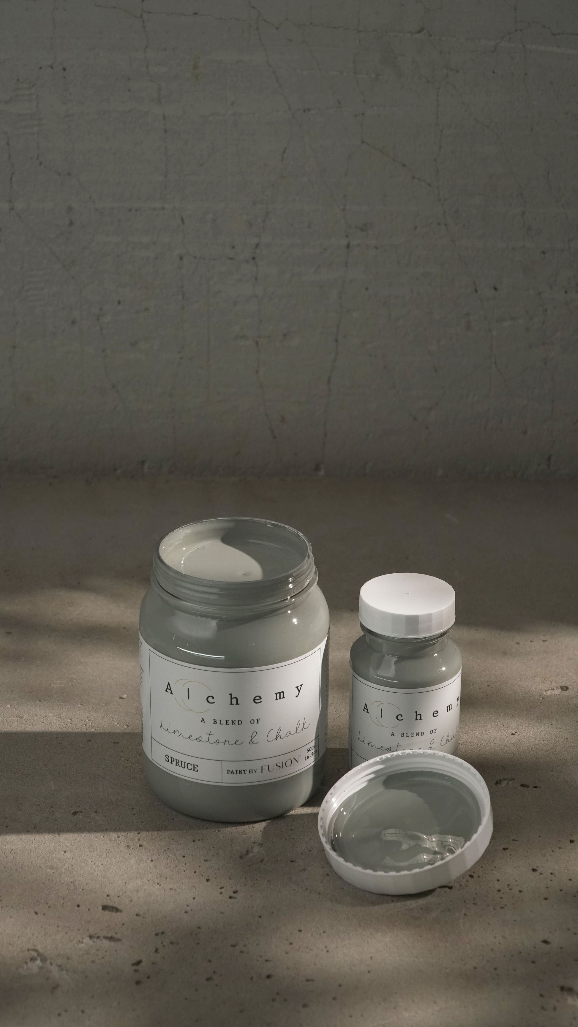 A jar of Alchemy by Fusion chalk paint in a gray color, with a label that includes the product name and the brand's logo.