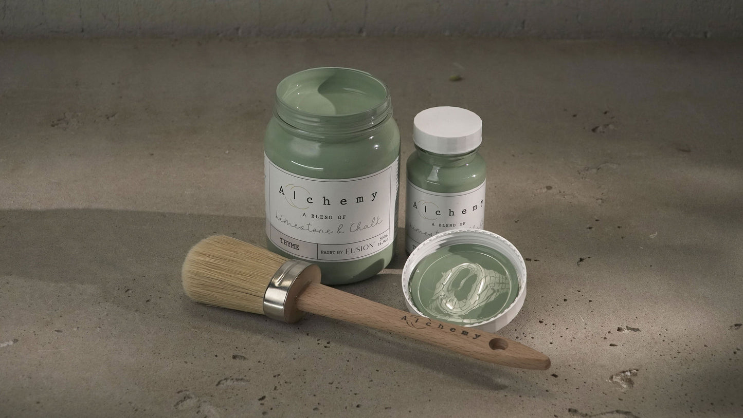 A jar of Alchemy by Fusion chalk paint in a thyme green color, with a white lid and a label that includes the product name and the color 'Thyme'.