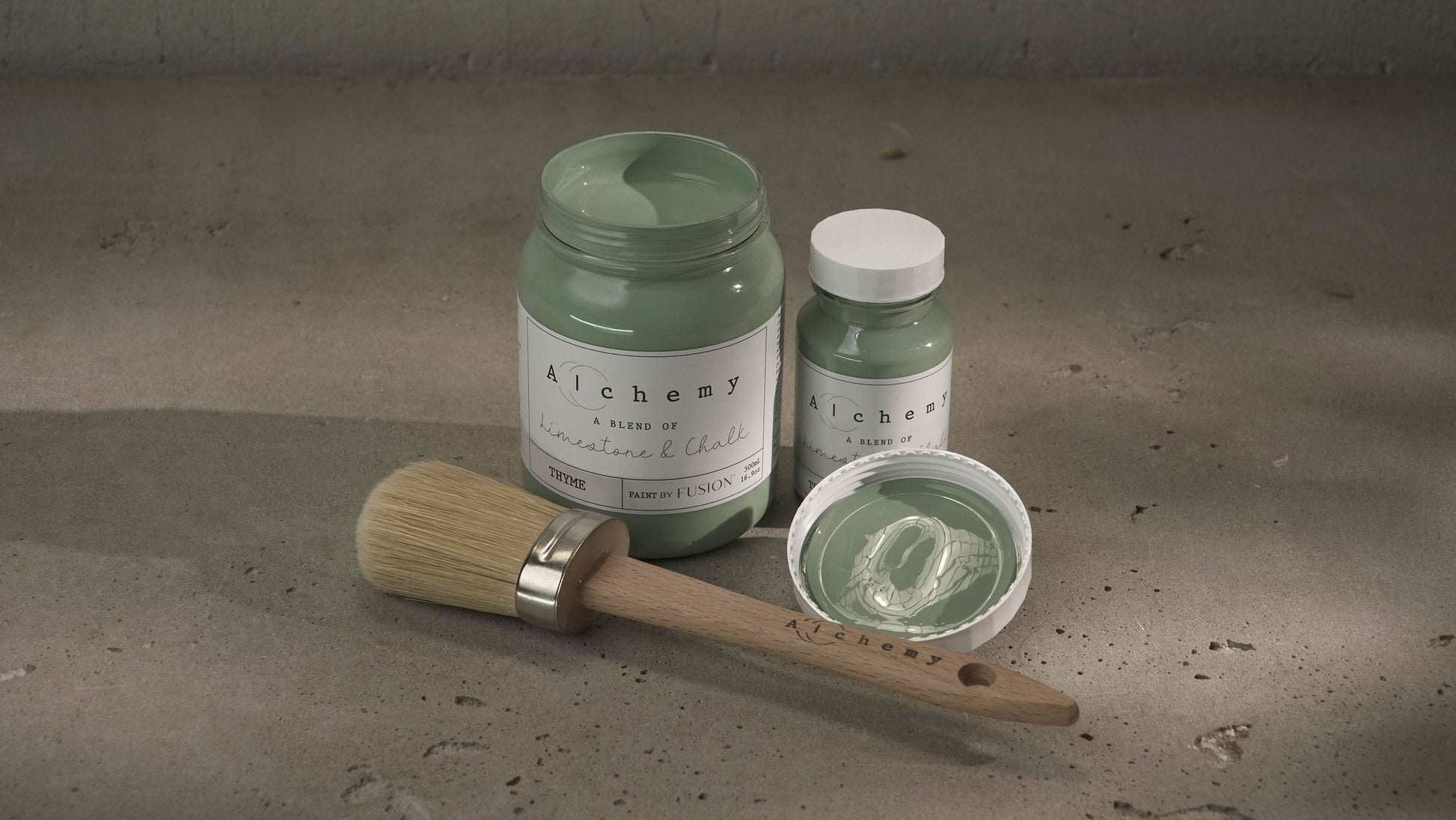 A jar of Alchemy by Fusion chalk paint in a thyme green color, with a white lid and a label that includes the product name and the color 'Thyme'.