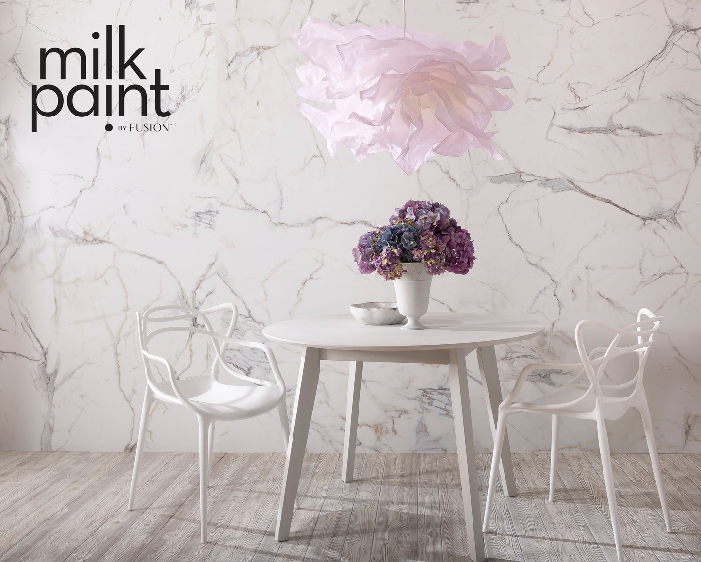 Dining area with a table and chairs against a marble wall, featuring 'milk paint' branding.
