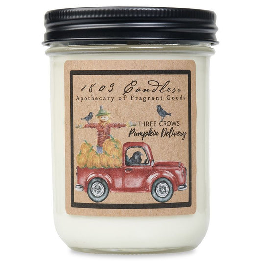 Candle jar with a decorative label featuring a red truck and pumpkins on a white background